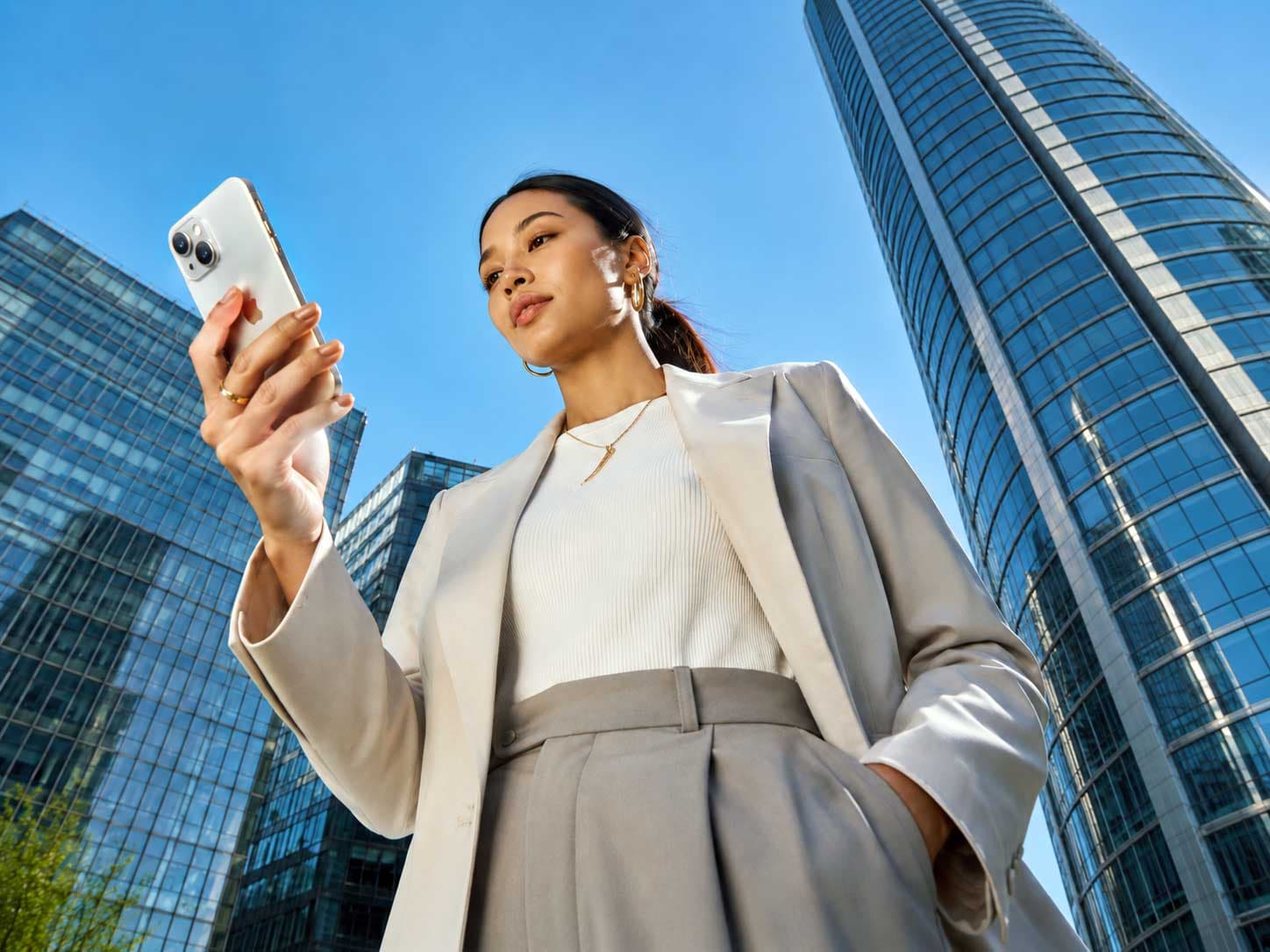 Woman checking her phone outside glass office towers